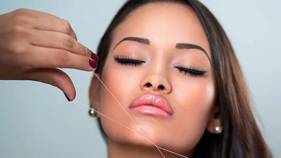 Facial threading: thread removing fine hair along the face